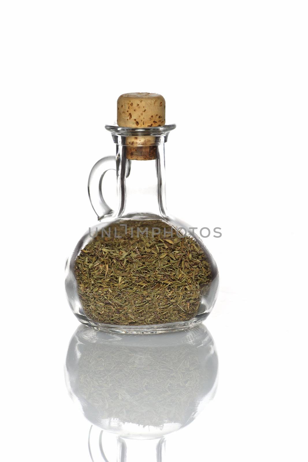Thyme in a glass bottle with a cork and isolated with reflection on white