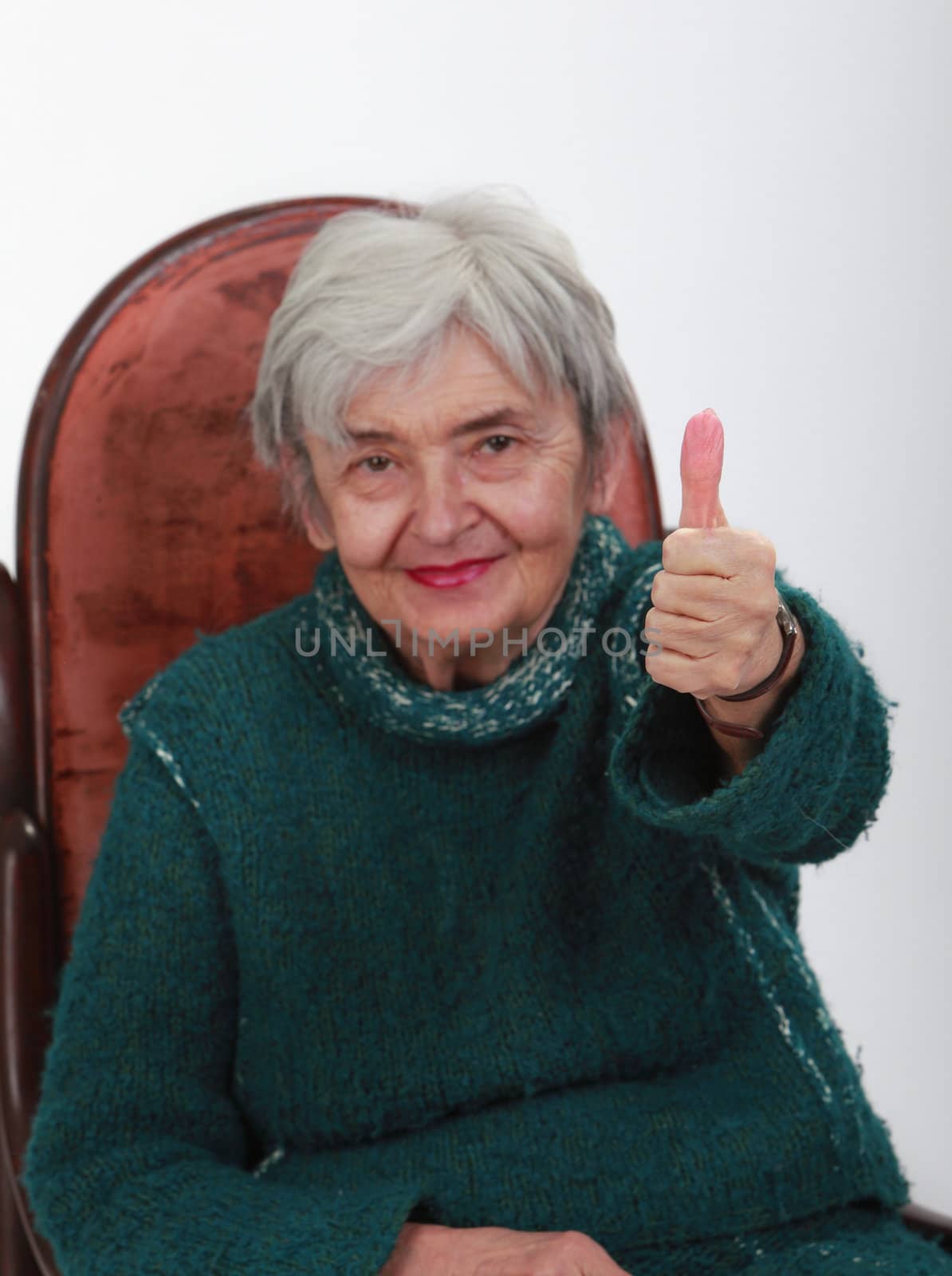 Image of a happy senior woman with thumb up.Selective focus on the hand.