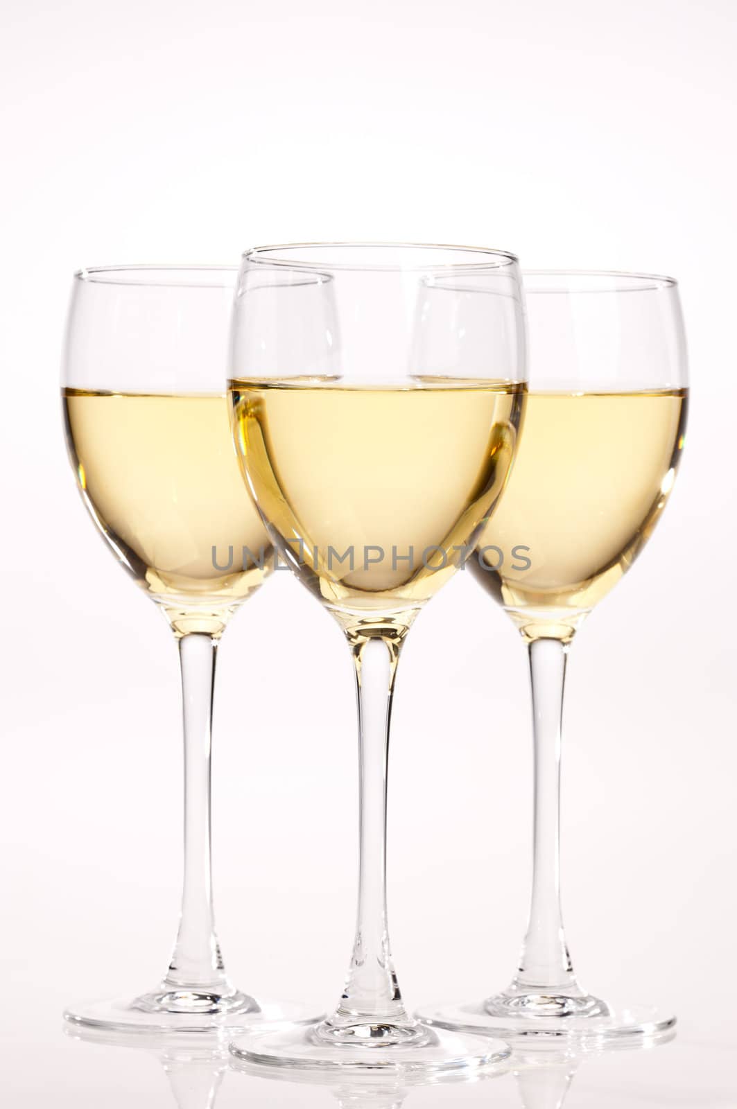 three glasses with white wine over light bsckground