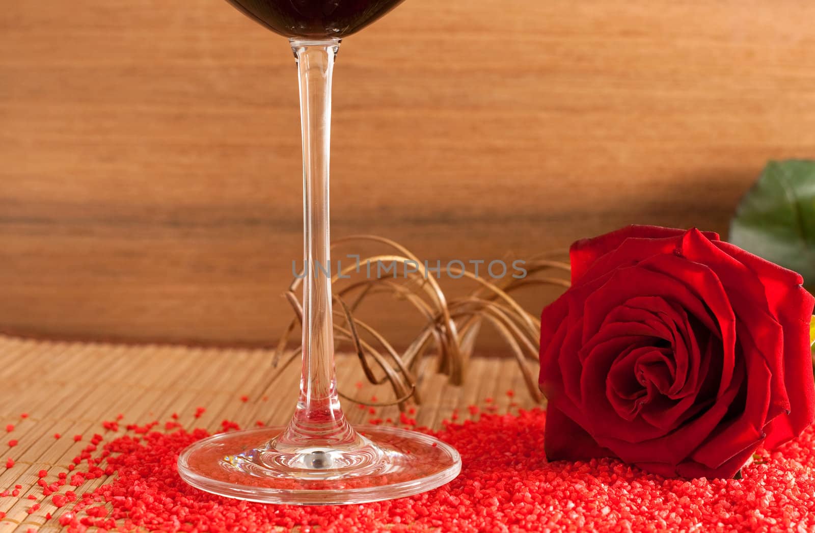 A red rose and a wine glass on a wooden bottom isolated on white background