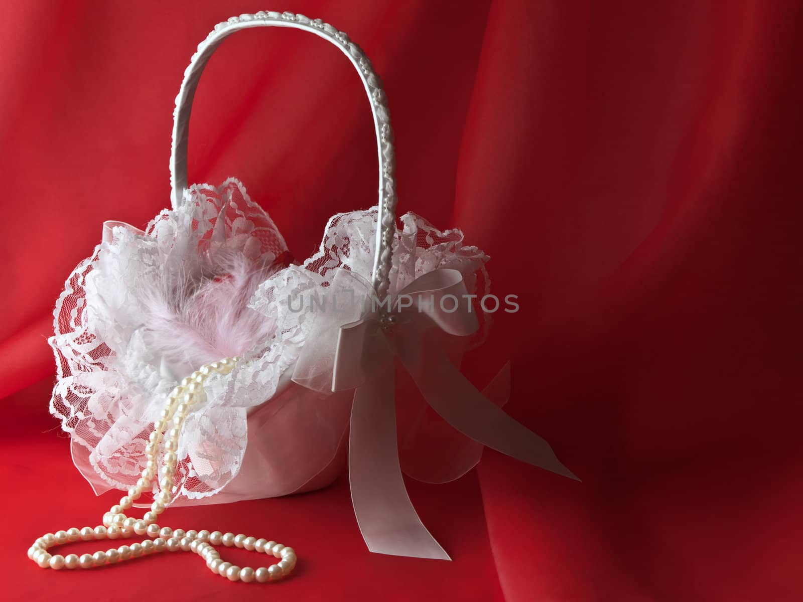 bridal white flower basket with pearl beads over red drapery