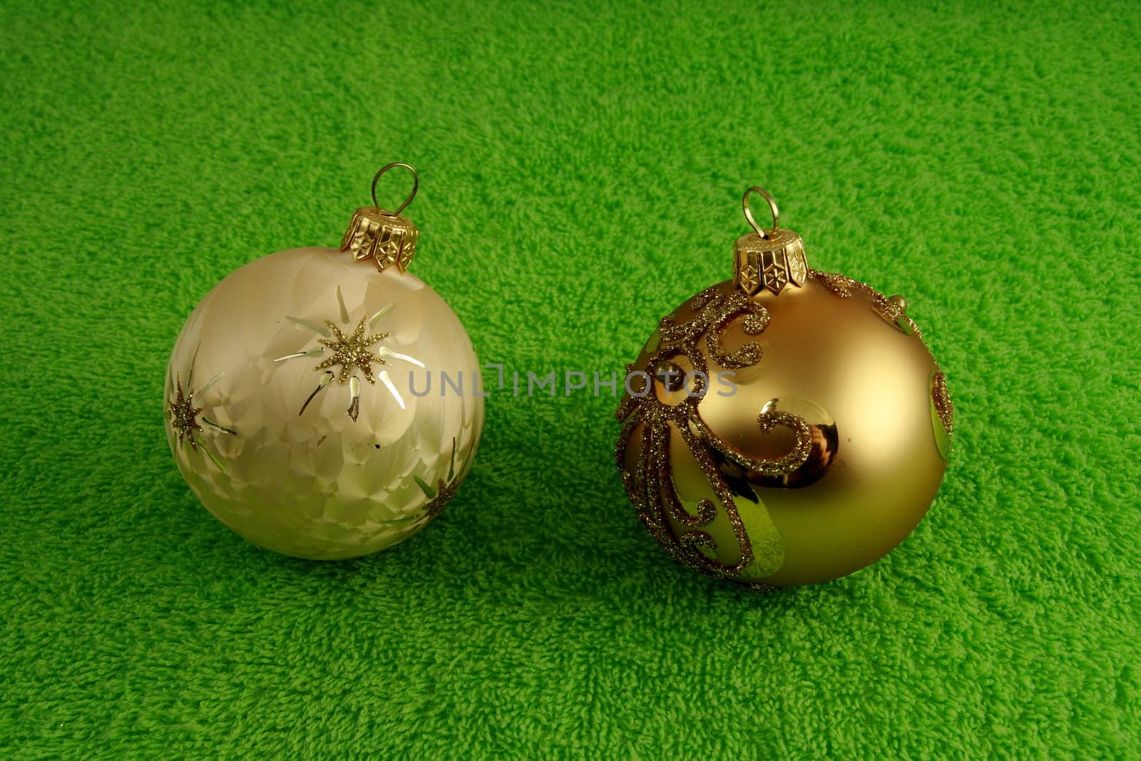 two xmass balls on soft green surface