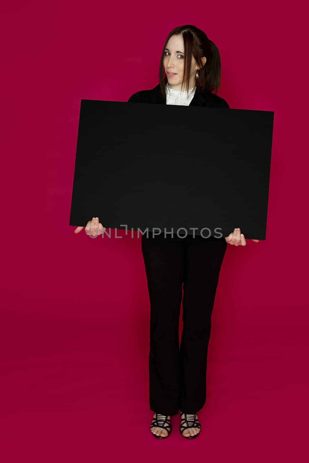 Young business woman wearing a business suit standing behind a black board against pink background