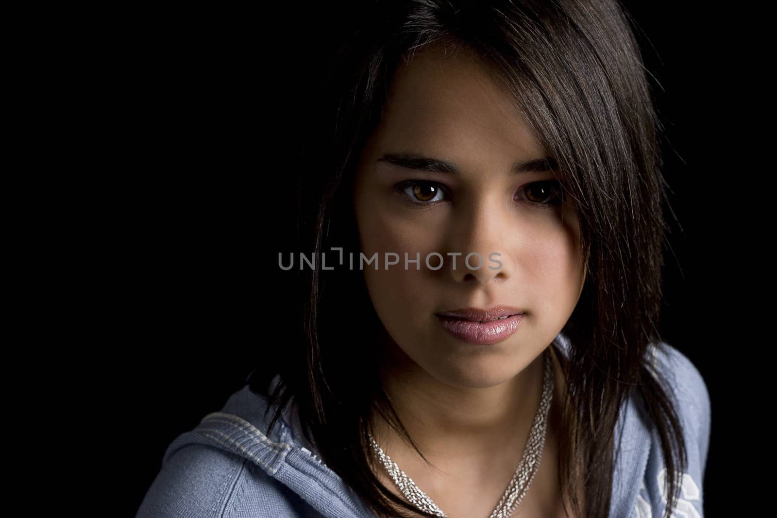 Head shot of a teen girl against a black background