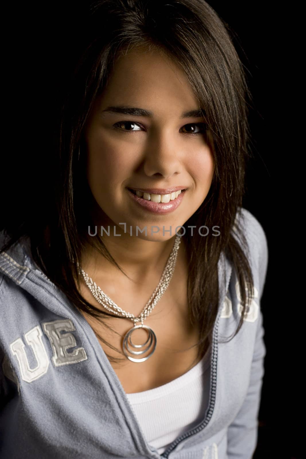 Teen girl smiling against a black background