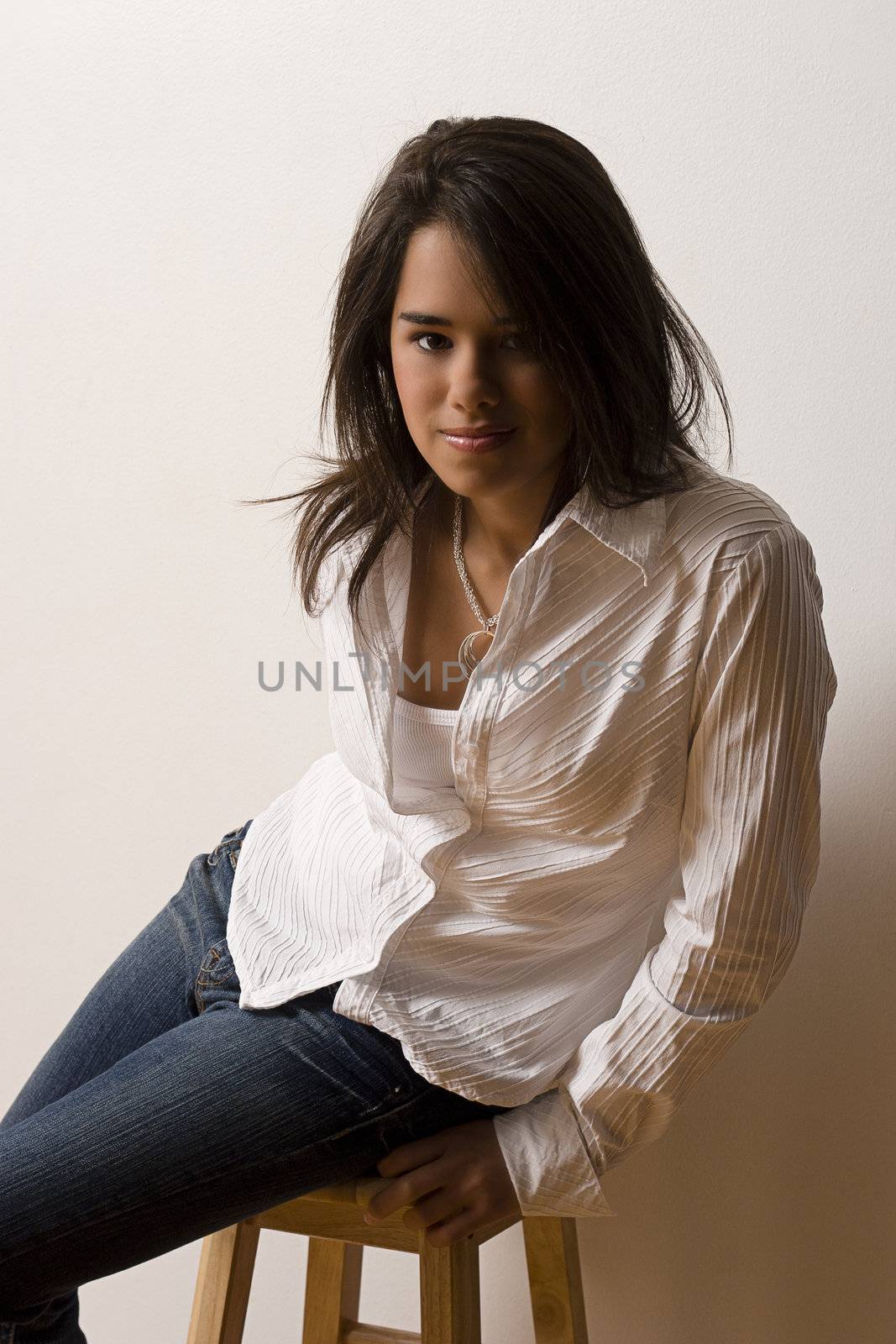 Young woman with white blouse and jeans sitting on a stool