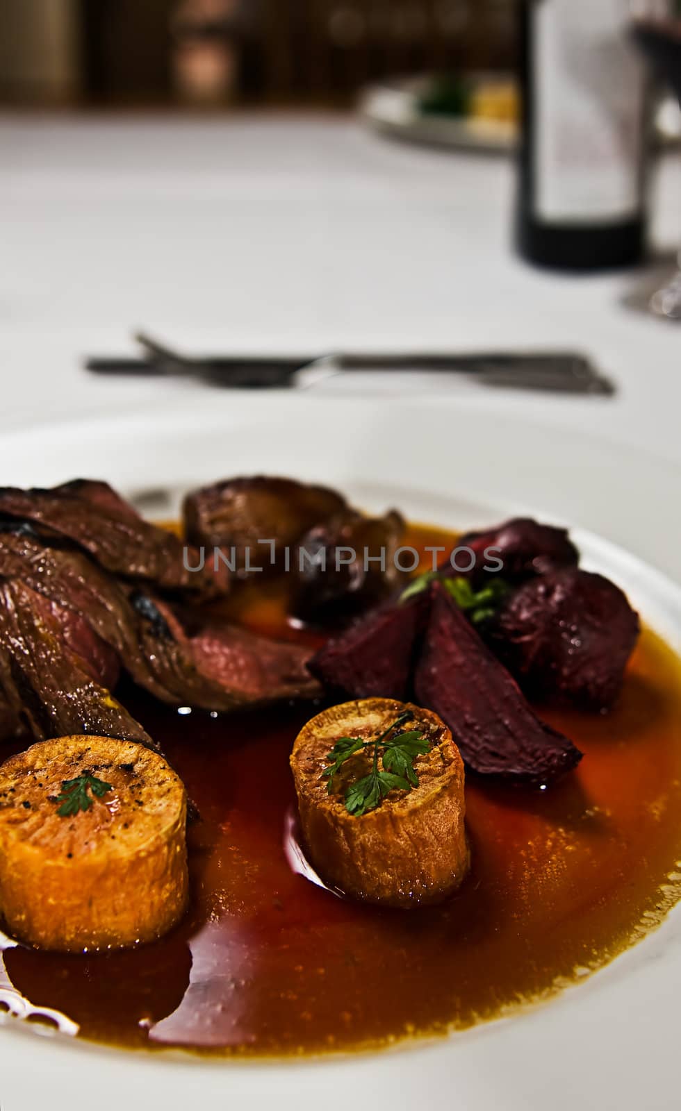 A dish of kangaroo meat with roasted beetroot and sweet potato in a gravy sauce.