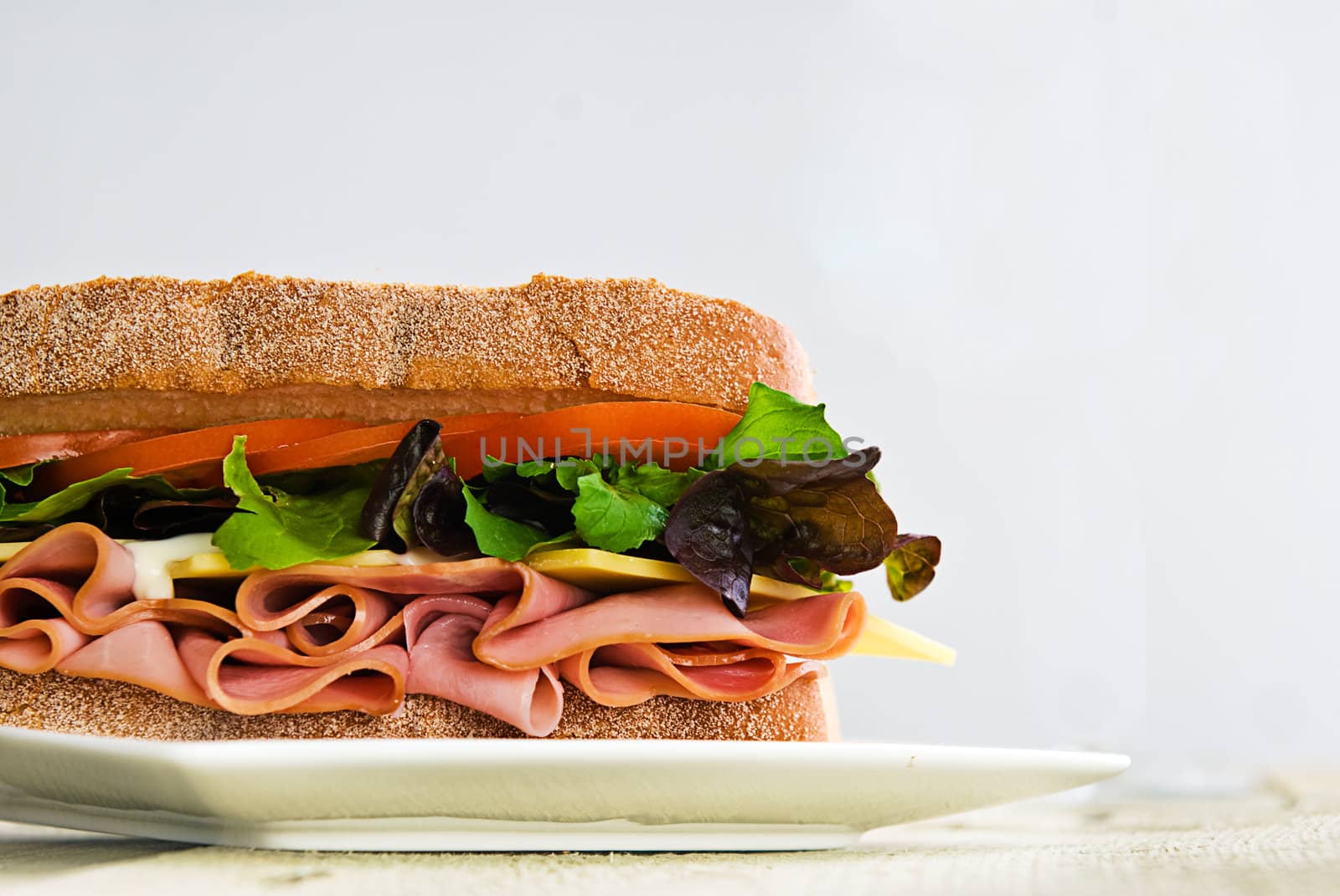 A gourmet sandwich of ham, cheese, lettuce, tomato and mayonaise isolated on white.