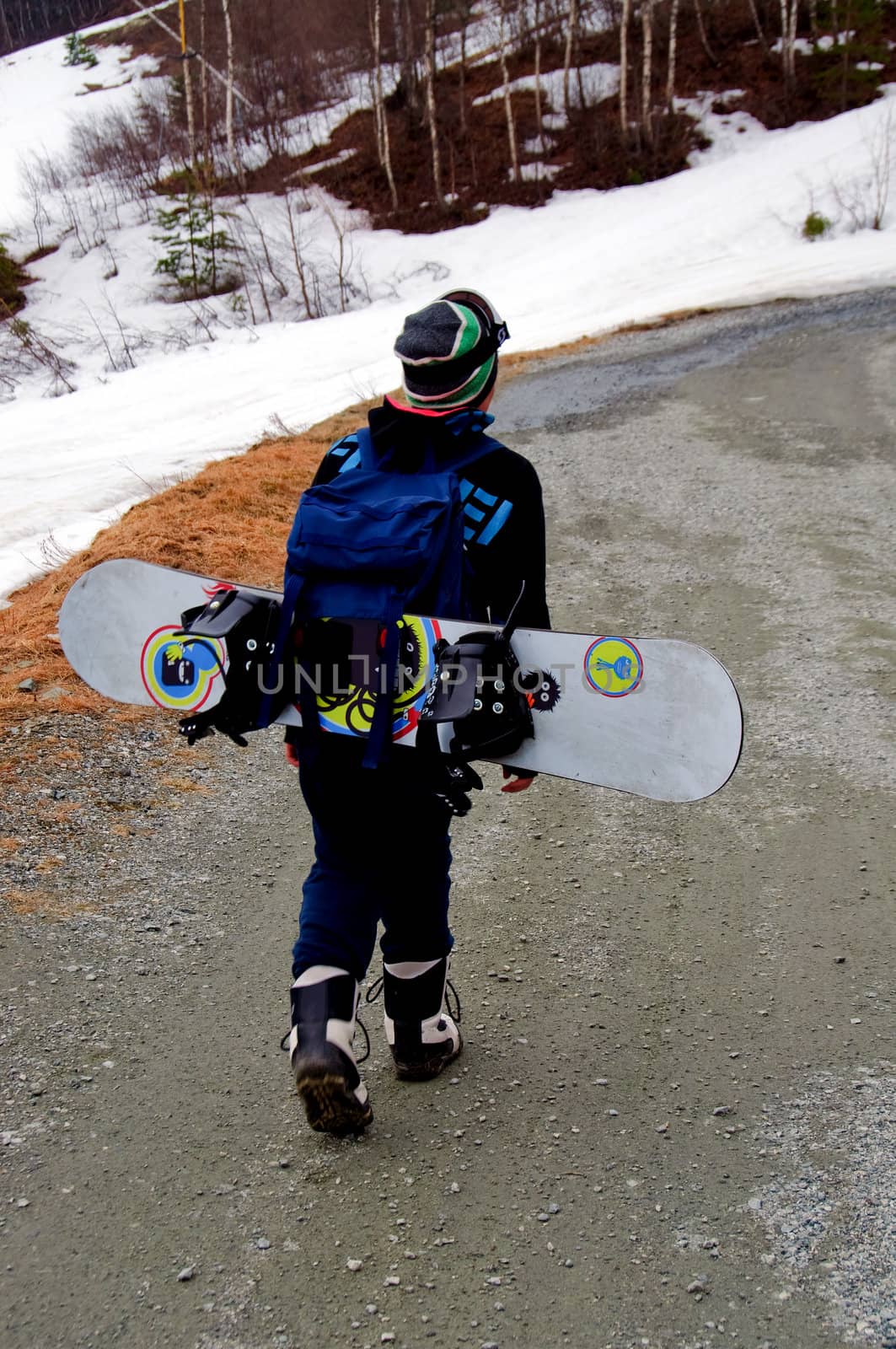 A young boy with his snowboard tied to a backpack
