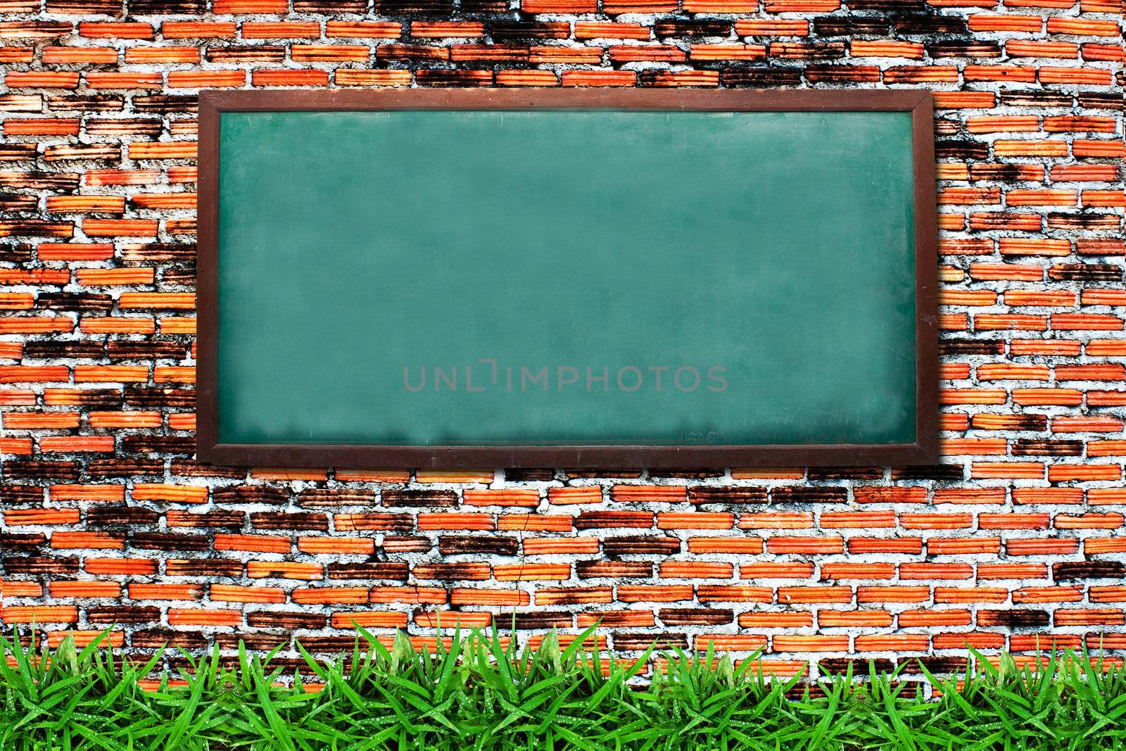 Chalkboard and green grass on grunge brick wall