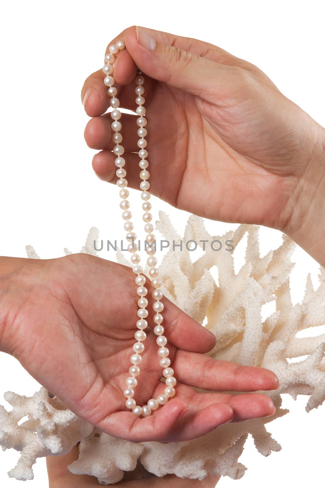 a pearl necklace in her hands against the backdrop of coral isolated on a white background