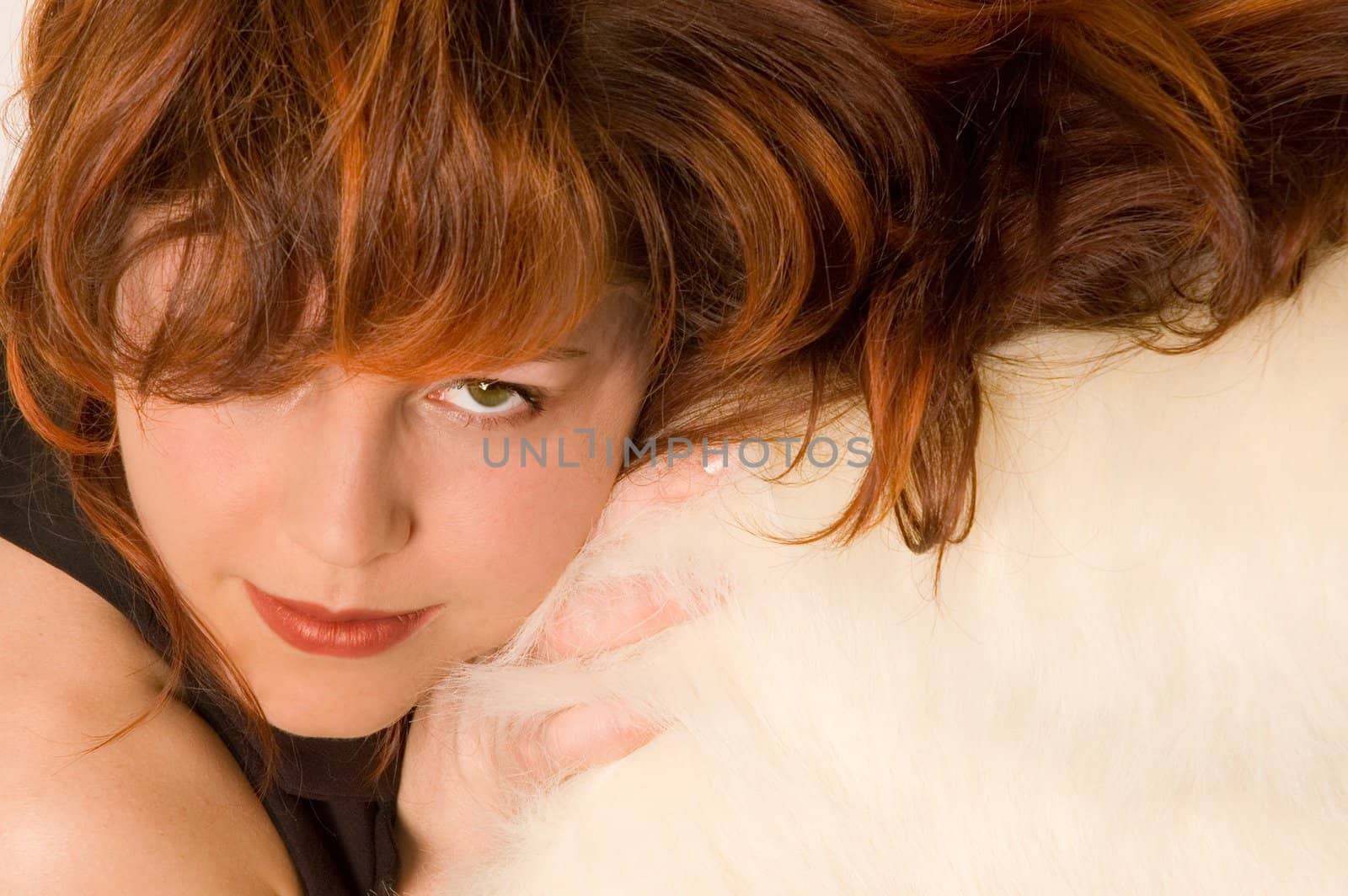 Young woman with red hairs, laying on the white carpet. Green eye looking strait into the camera