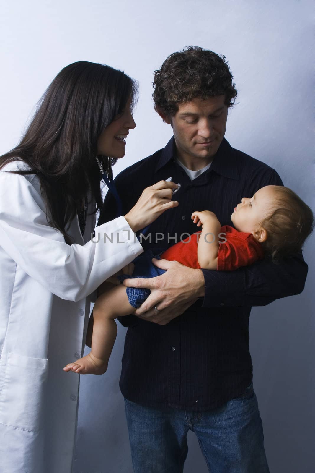 Father holds his young child for doctor to examine with a joyful smile.