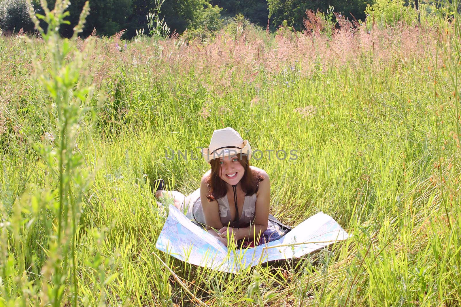 The girl on a summer meadow with a topographic map