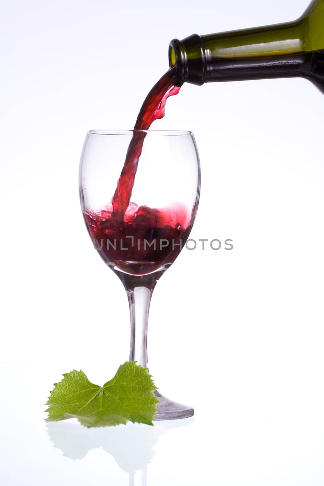 Pouring delicious red wine in a glass with reflection.