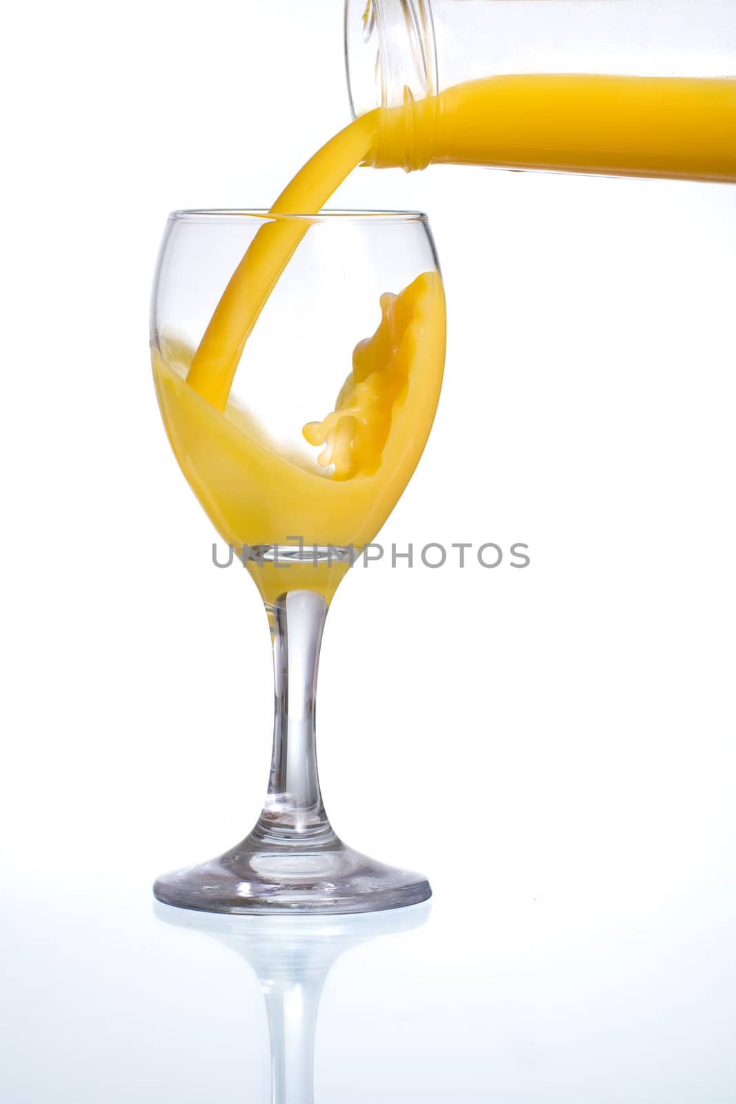 Pouring fresh orange juice in a glass with reflection