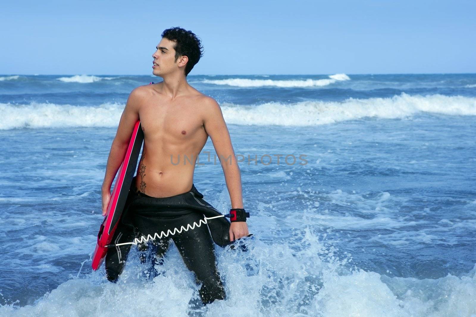 Beach summer beach portrait of young handsome surfer on waves