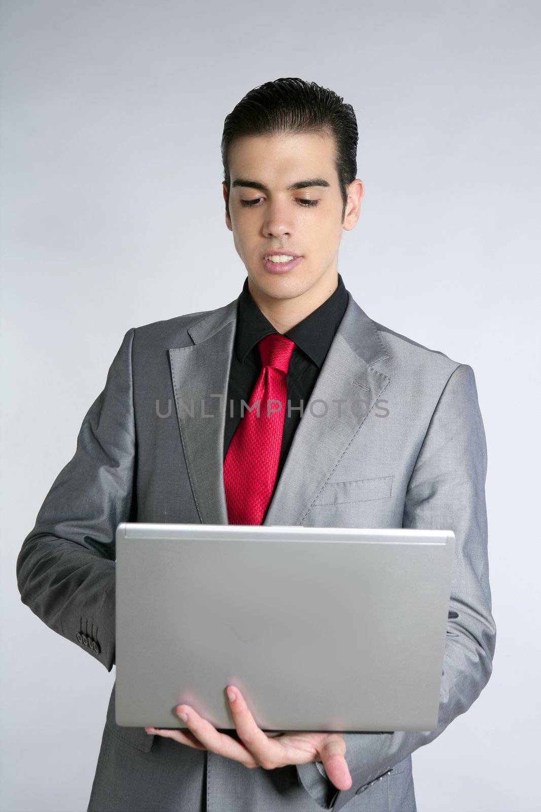 Businessman in gray suit holding laptop computer at studio