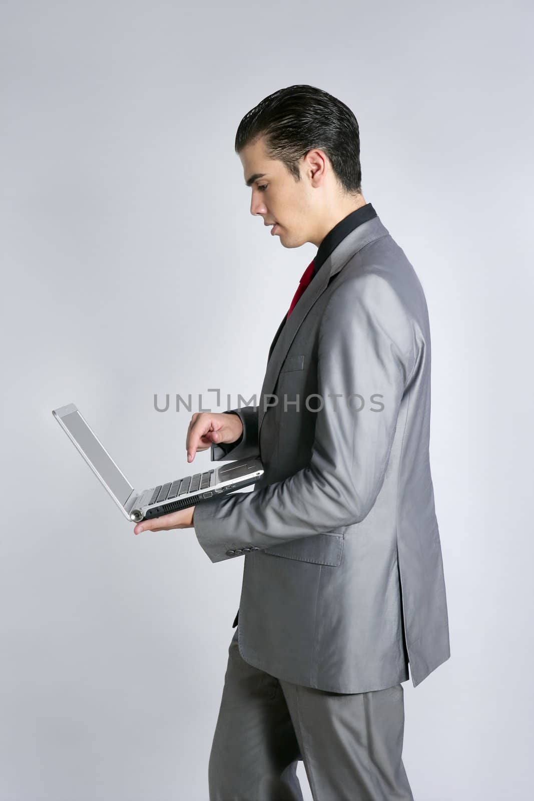 Businessman in gray suit holding laptop computer at studio