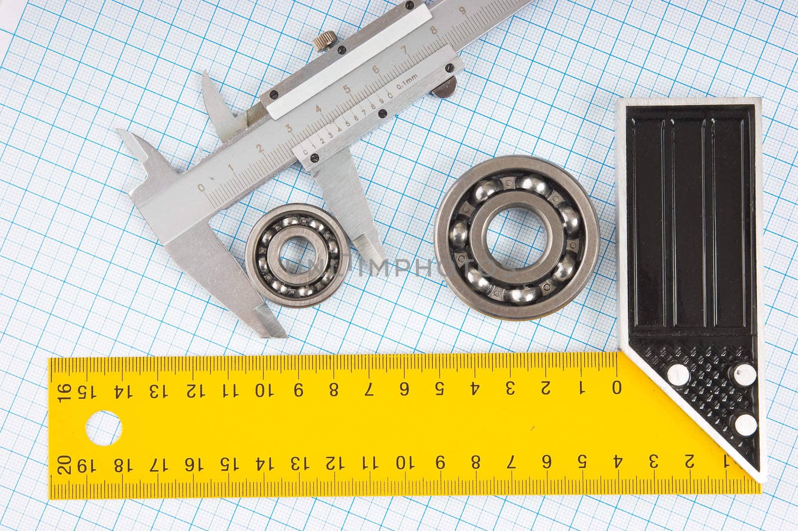 calipers, bearing and square on the background of graph paper