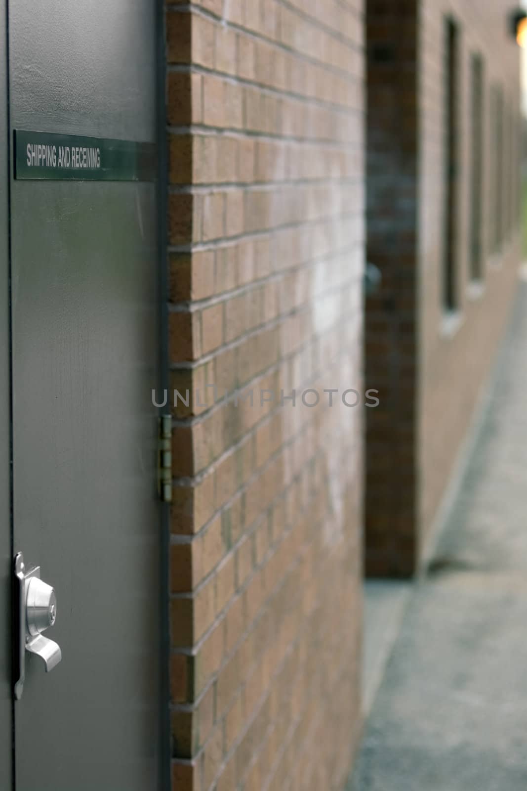 Shipping and Receiving door with nameplate & security lock in focus, the rest of the bricked building out of focus.