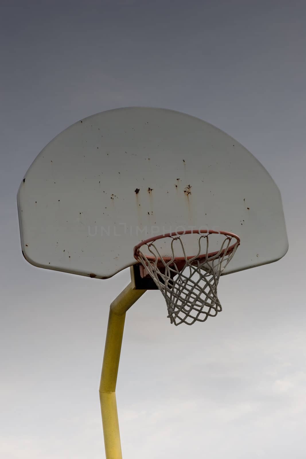 An isolated outdoor shot of a basketball net and backboard, with blue sky in the background.