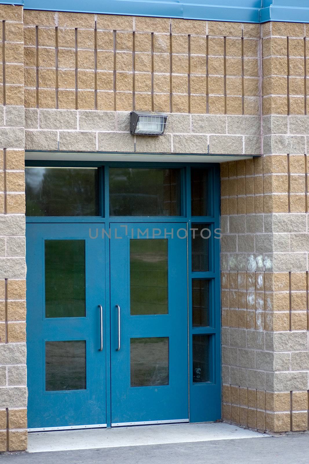 A set of blue school double doors surrounded by gray and brown brick.