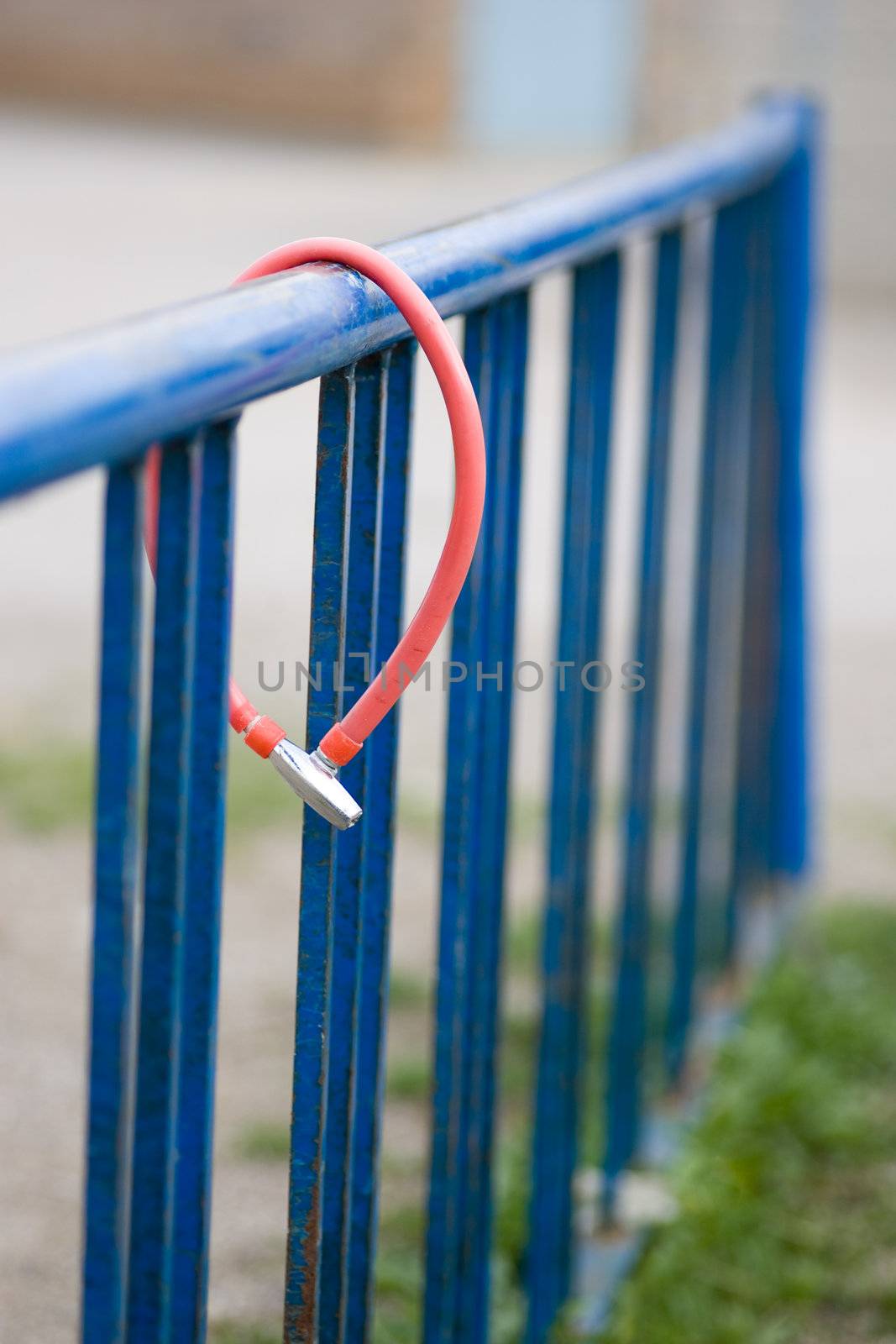 An empty blue bike rack, with a lone security cable left behind.