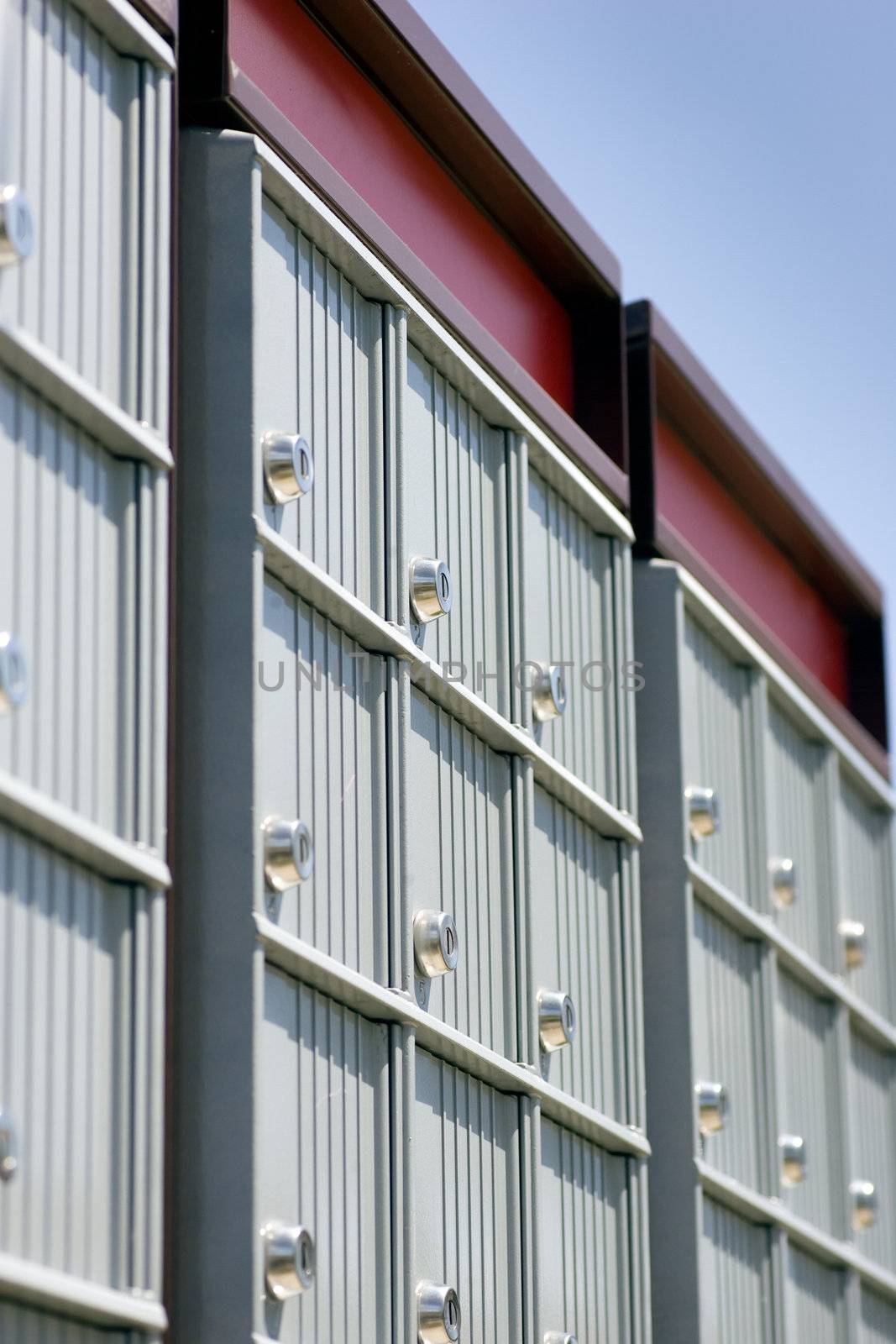 Looking up at a set of mailboxes, focus on the locks, with blue sky in the background.