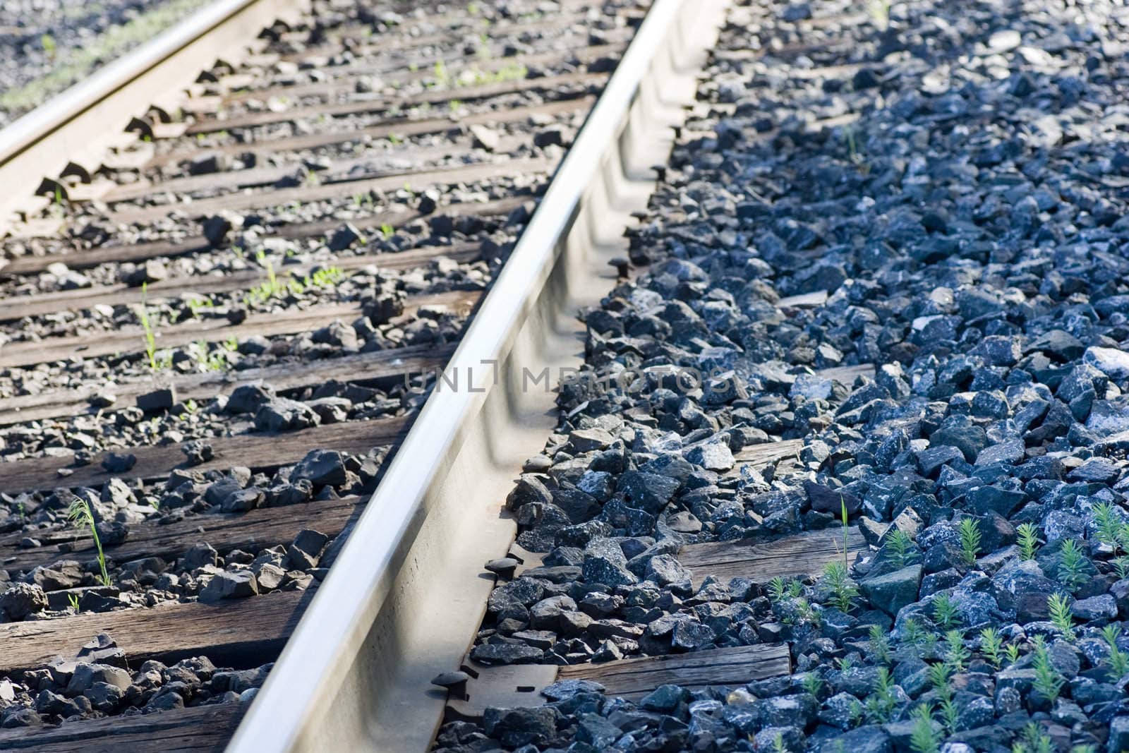 An isolated portion of train tracks, focus on the rail.