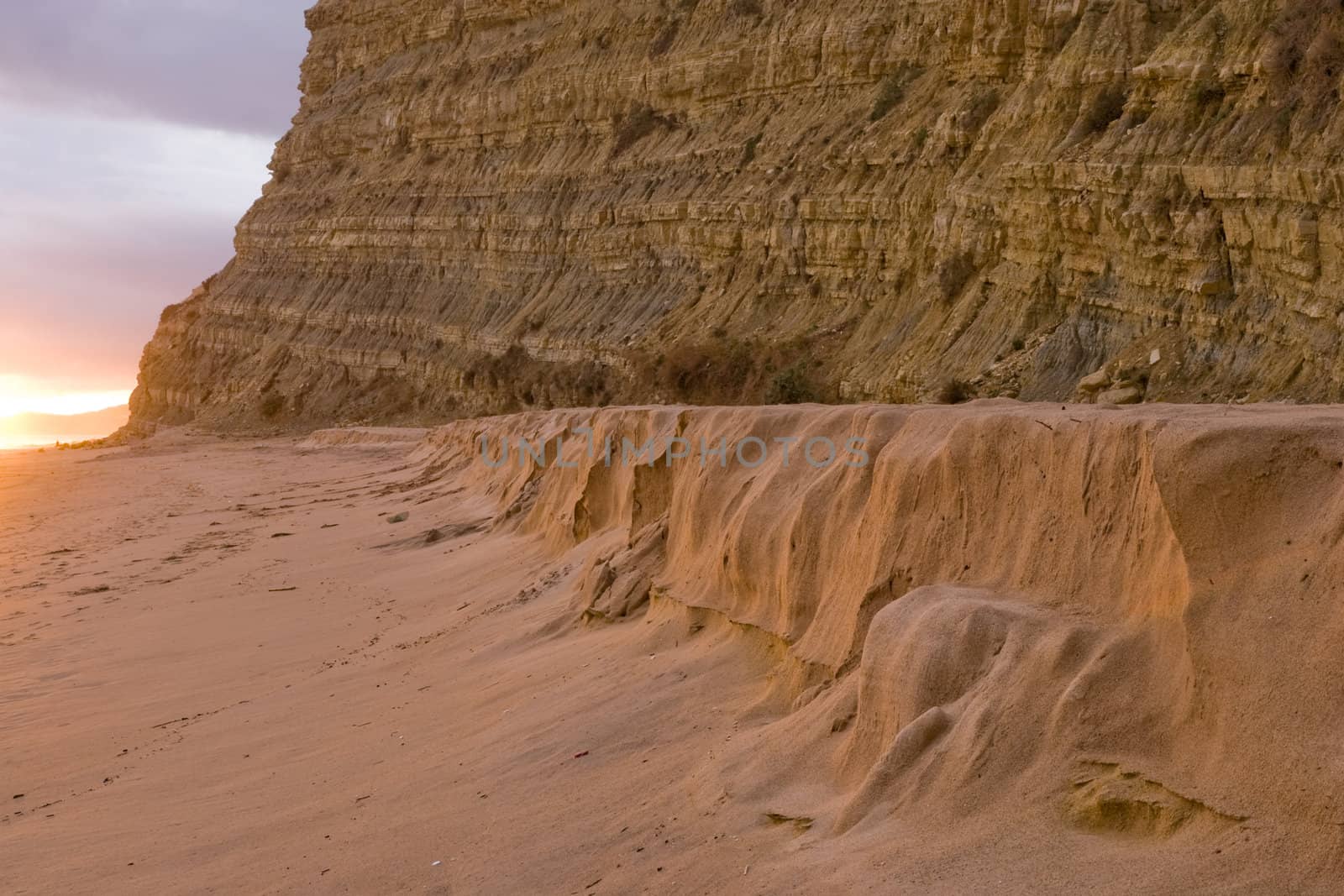 Beach meets cliff at sunset by woodygraphs