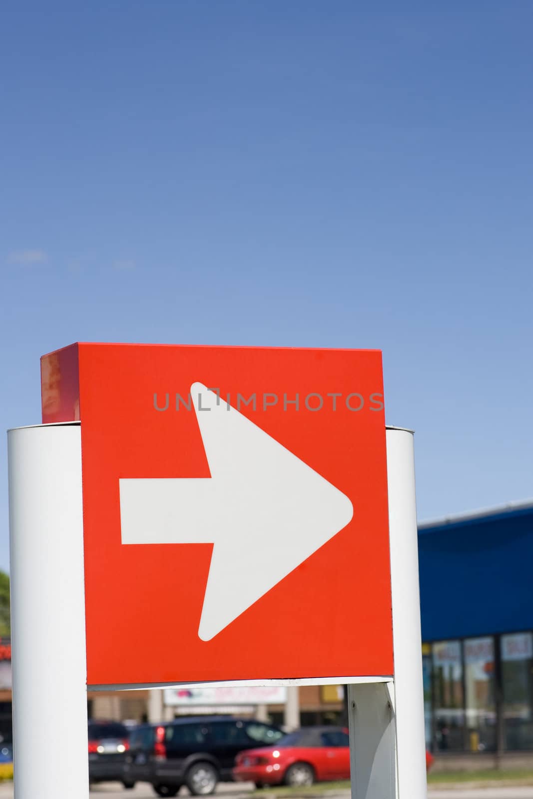 Directional sign in front of retail stores, with blue sky background.