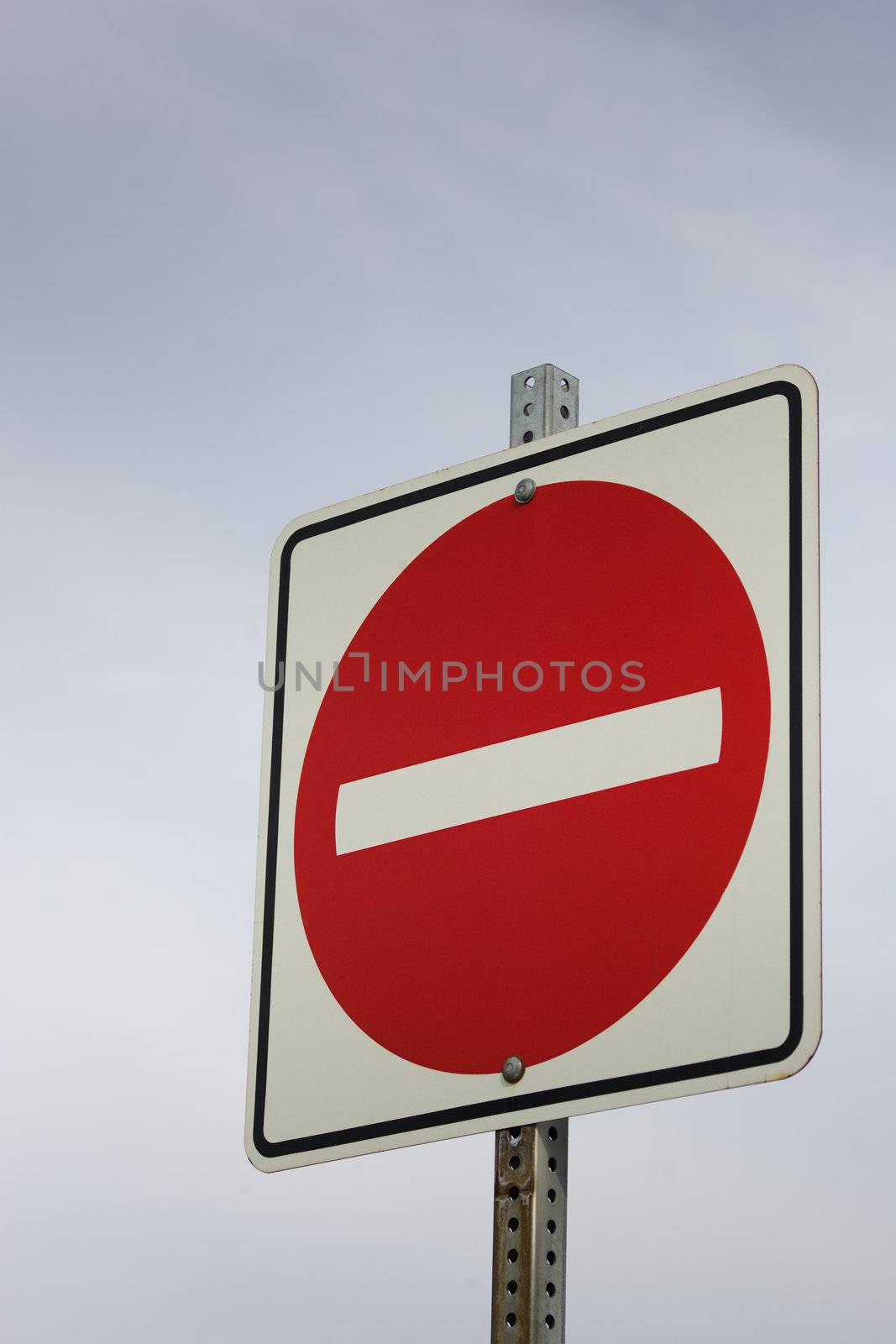 A red no entry sign against a sky background.