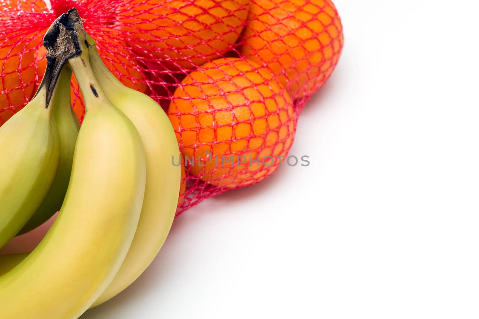 Bunches of Oranges in netting, and Bananas, isolated on white.