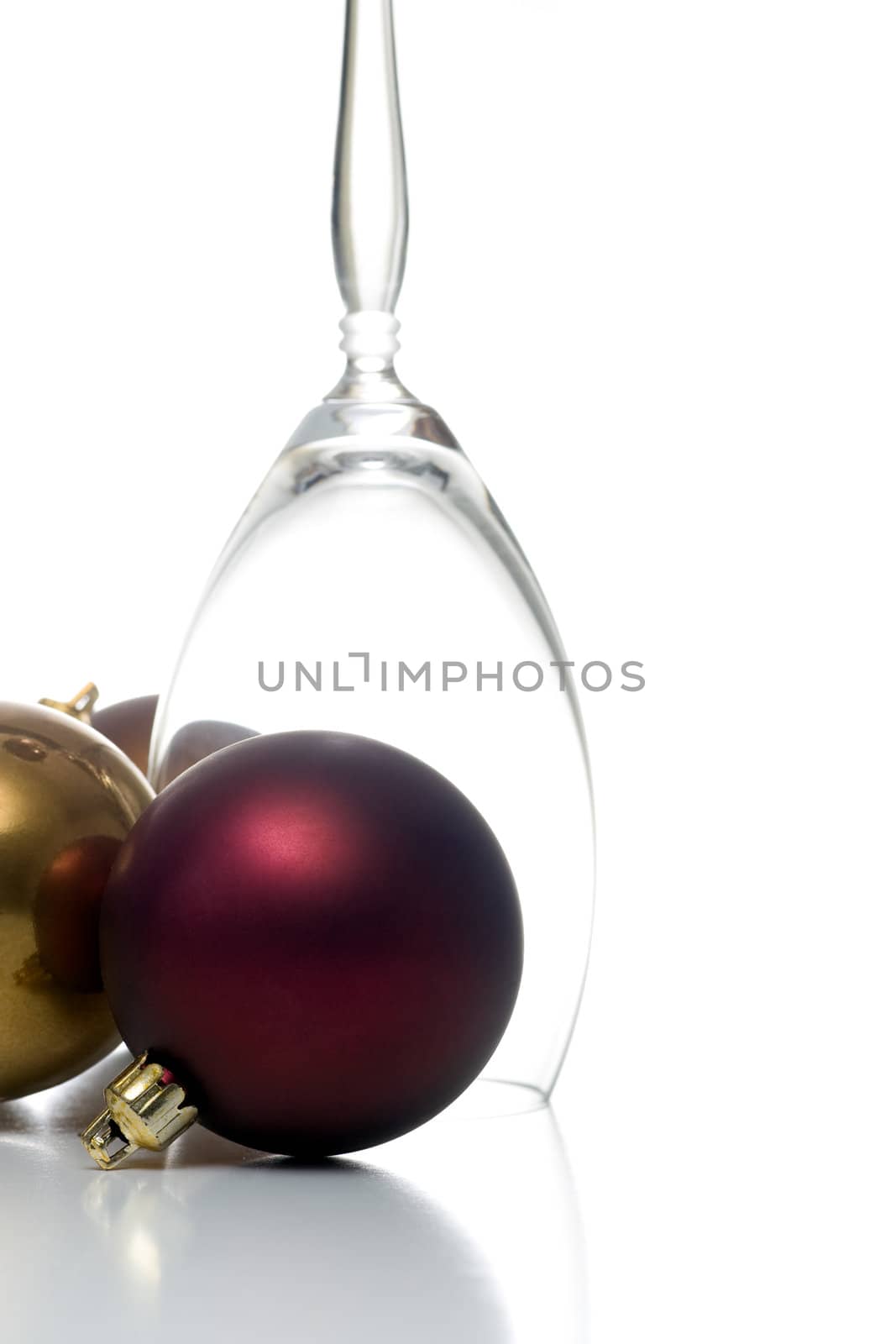 Single upside down champagne glass surrounded by christmas ornaments, isolated on white.