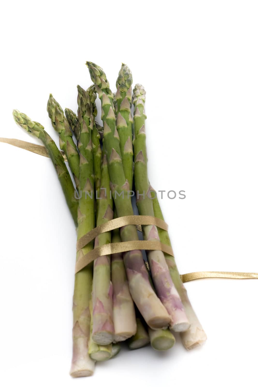 A bunch of asparagus, tied with gold ribbon, isolated on white.