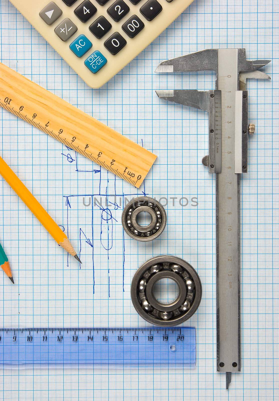 calipers, bearing and square on the background of graph paper