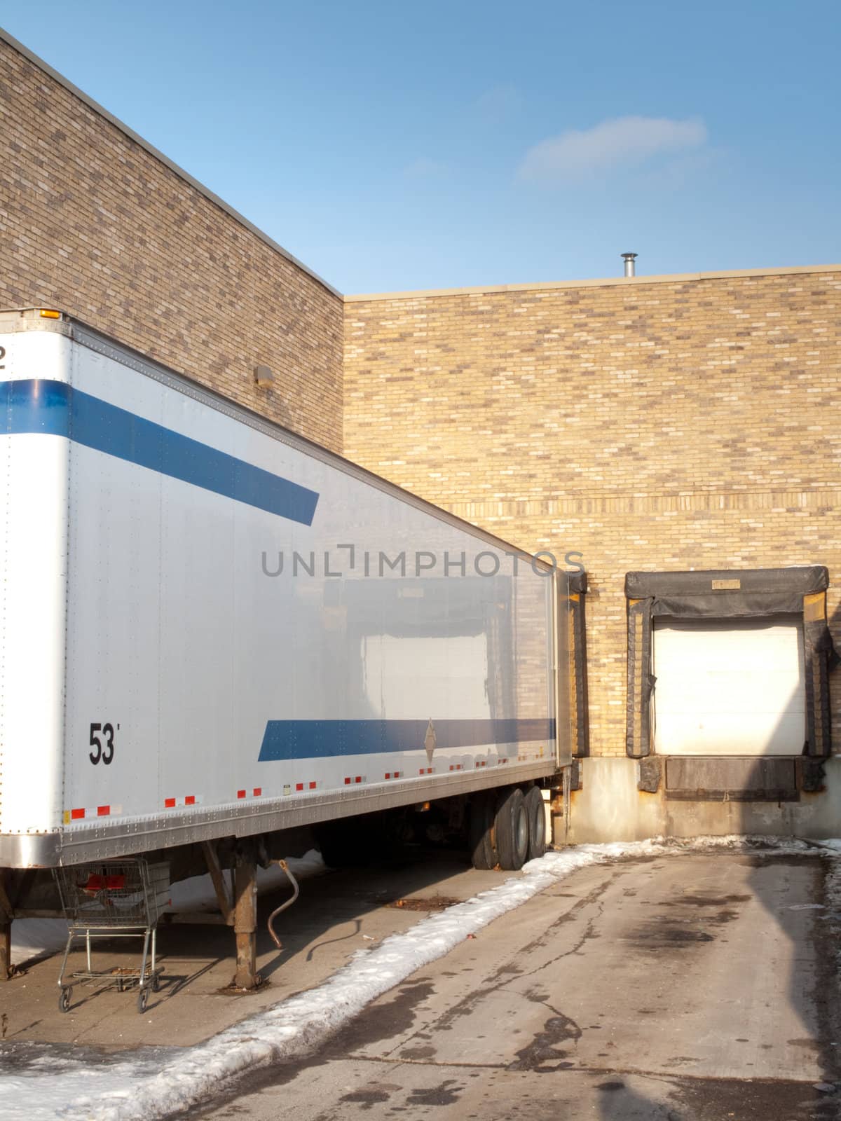 A loading dock with one empty bay and a trailer in the other bay.