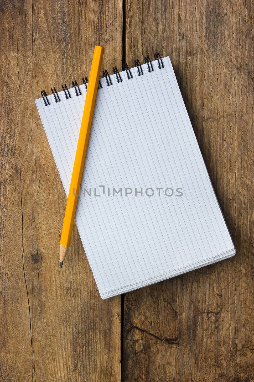 Notepad and pencil on the background of the old wooden planks