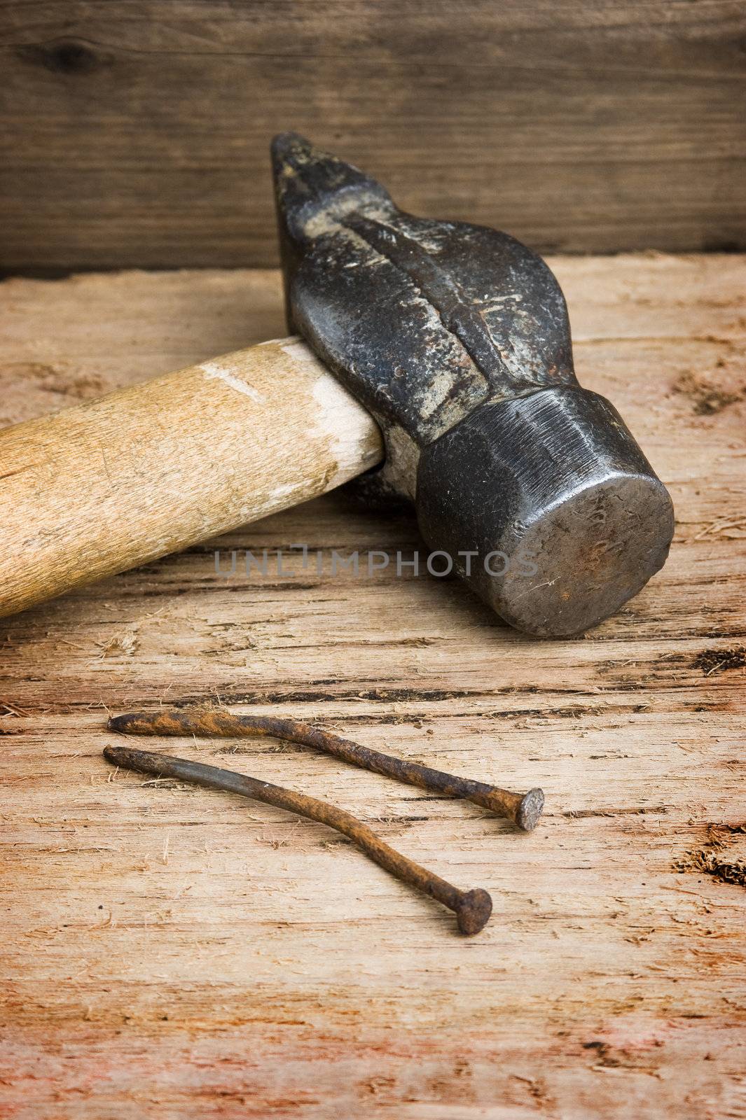 hammer with a rusty nail against a wooden board