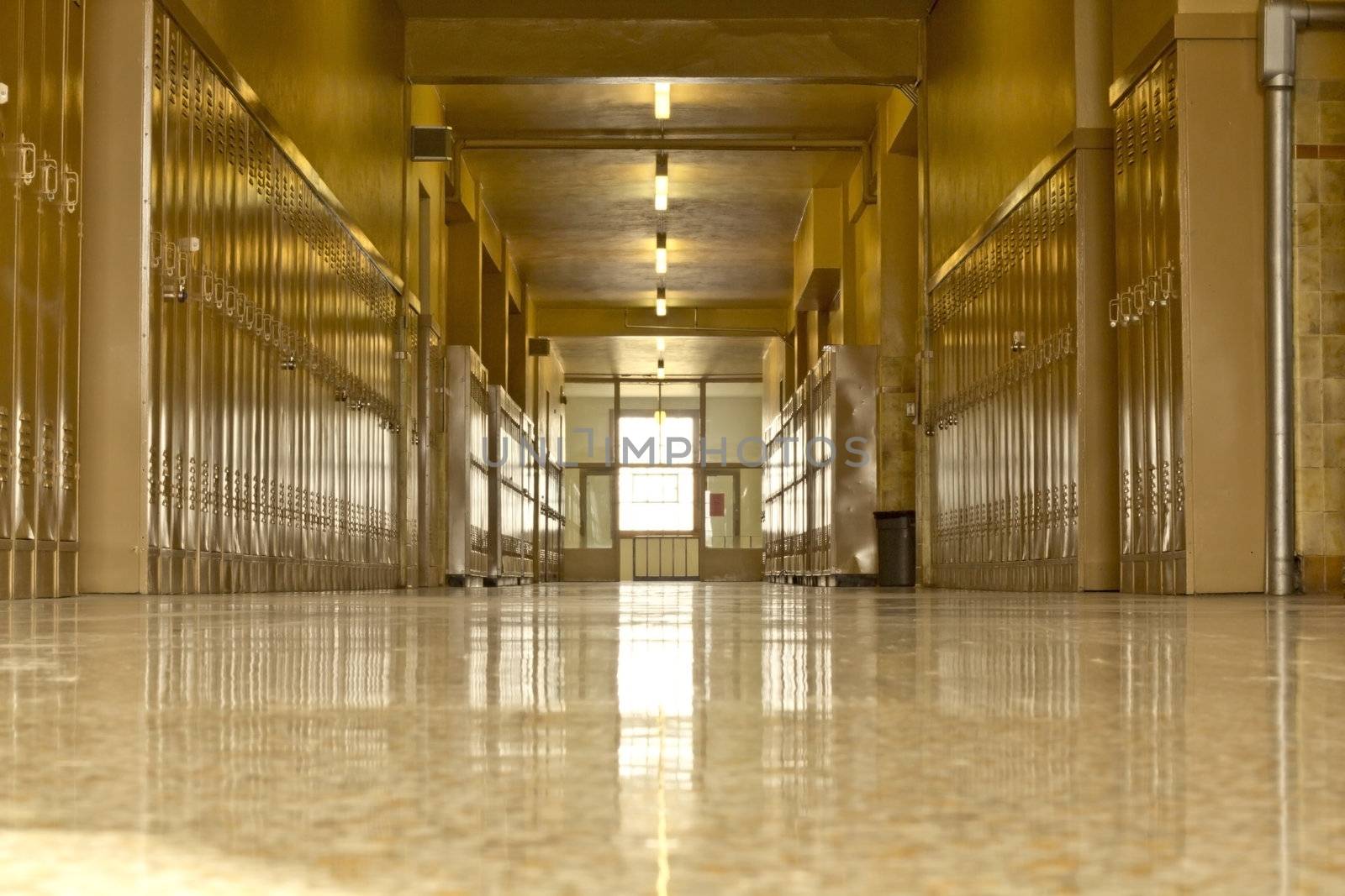 An empty high school corridor with a bright light at the end of the hallway