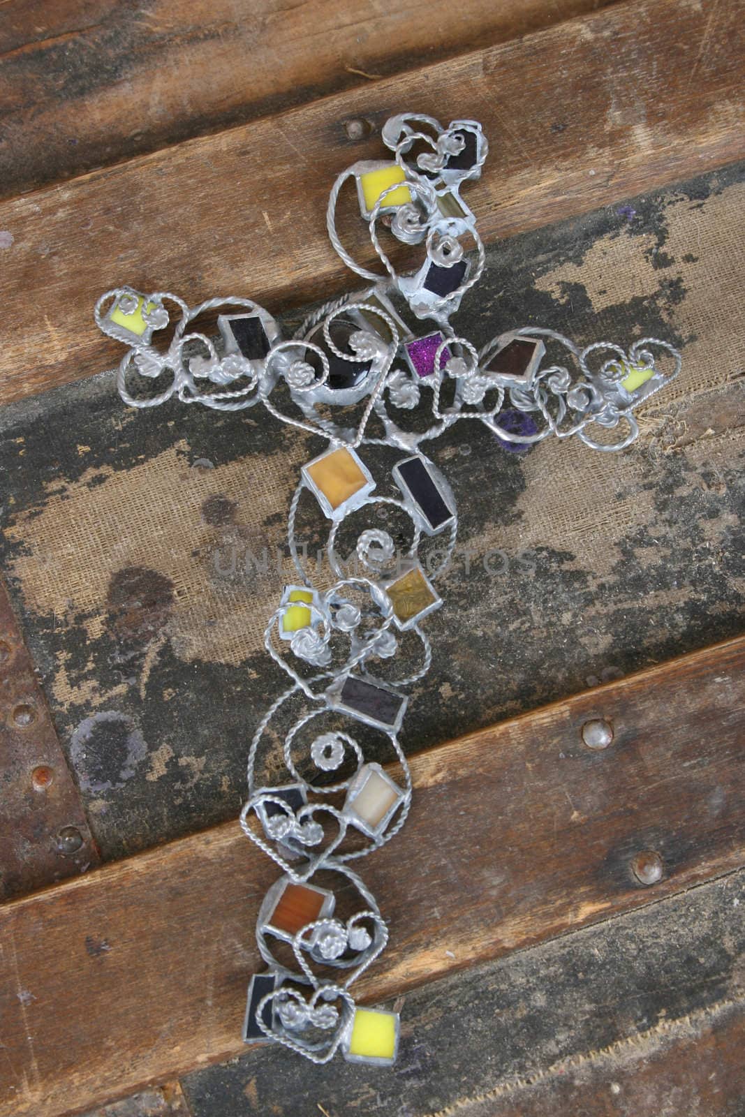 Ornate stained glass and wire cross on an antique chest
