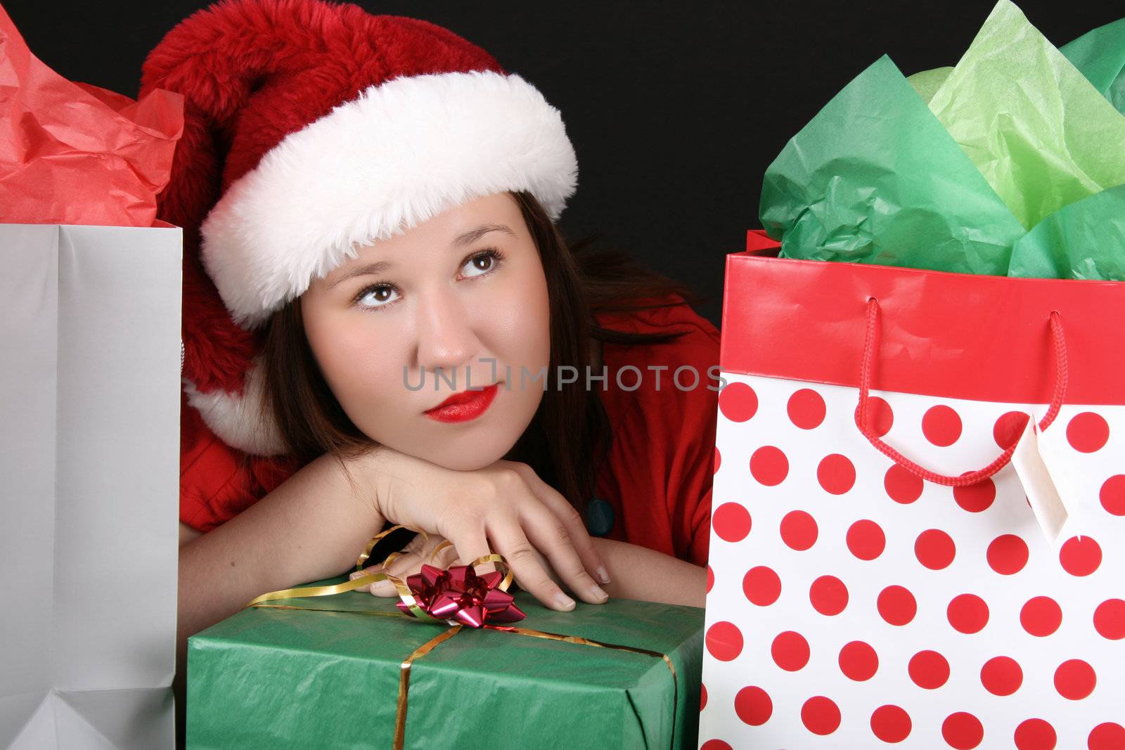 Beautiful caucasian brunette dreaming about christmas amongst gifts