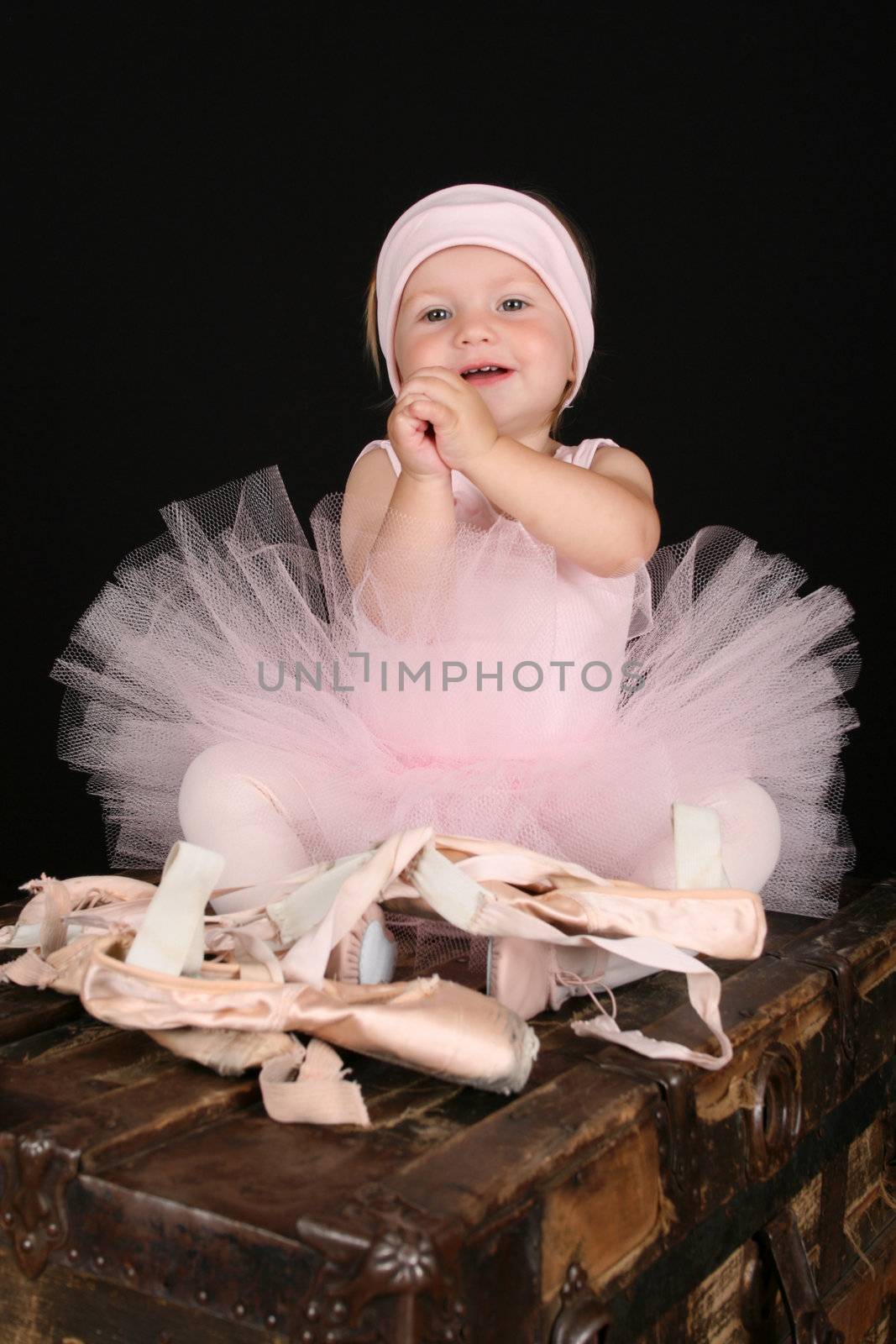 Baby ballerina sitting on an antique trunk