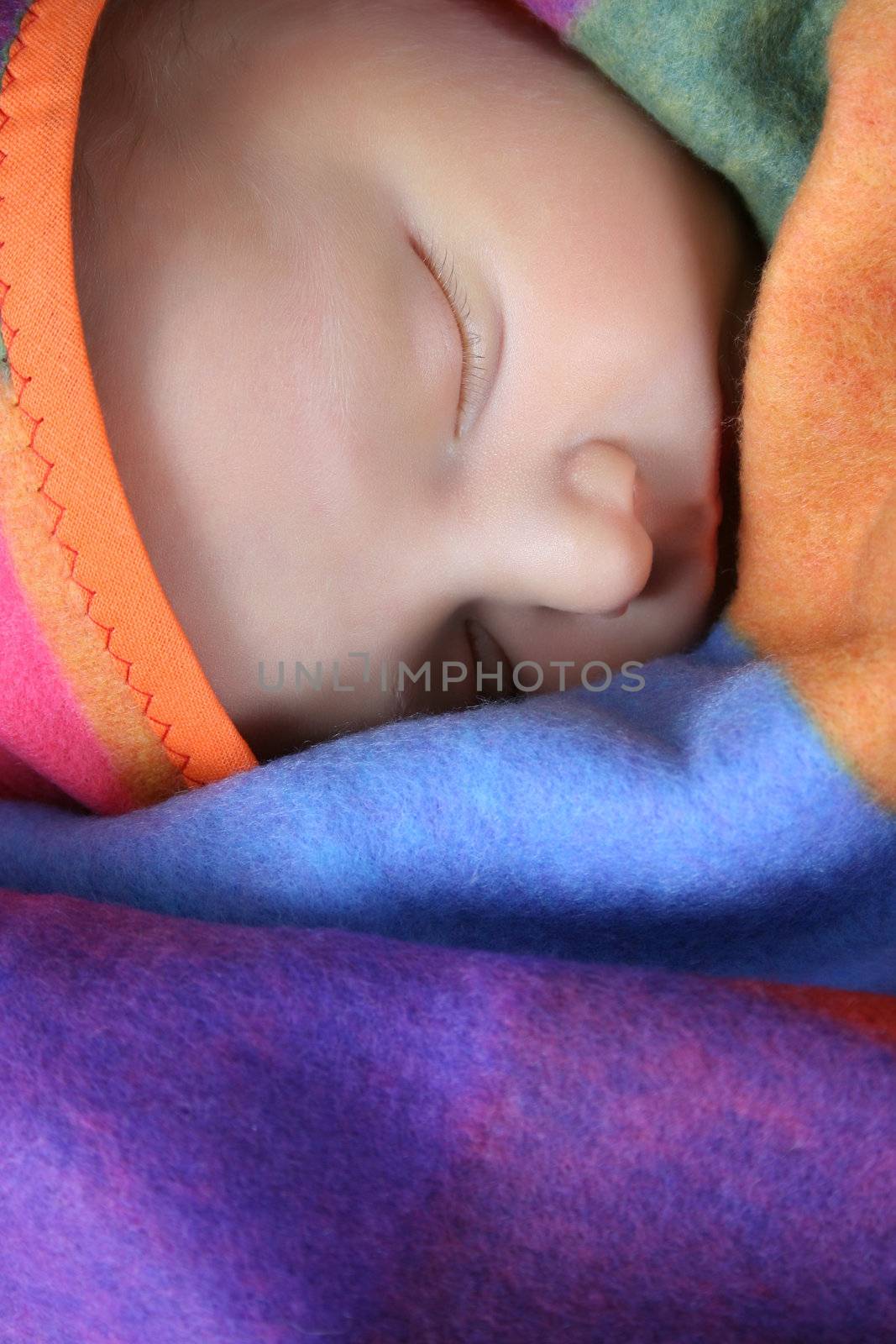 Beautiful newborn boy wrapped in a colorful blanket