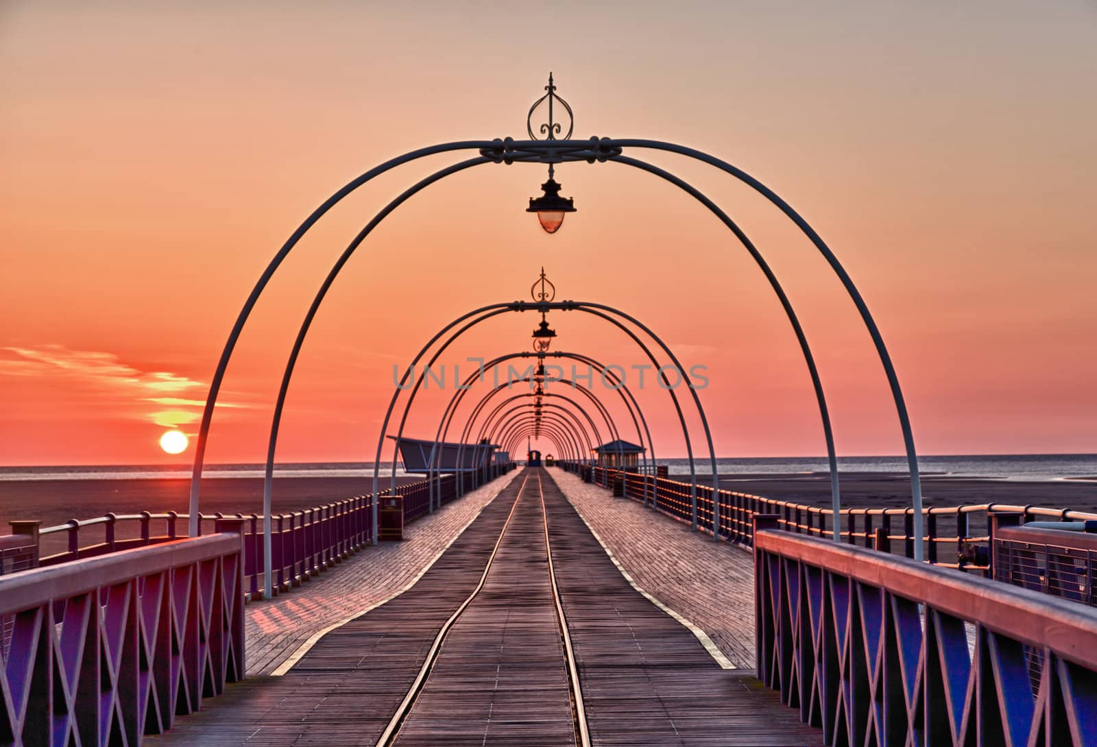 View down center of Southport Pier at sunset with the ornate lights framing the distant horizon