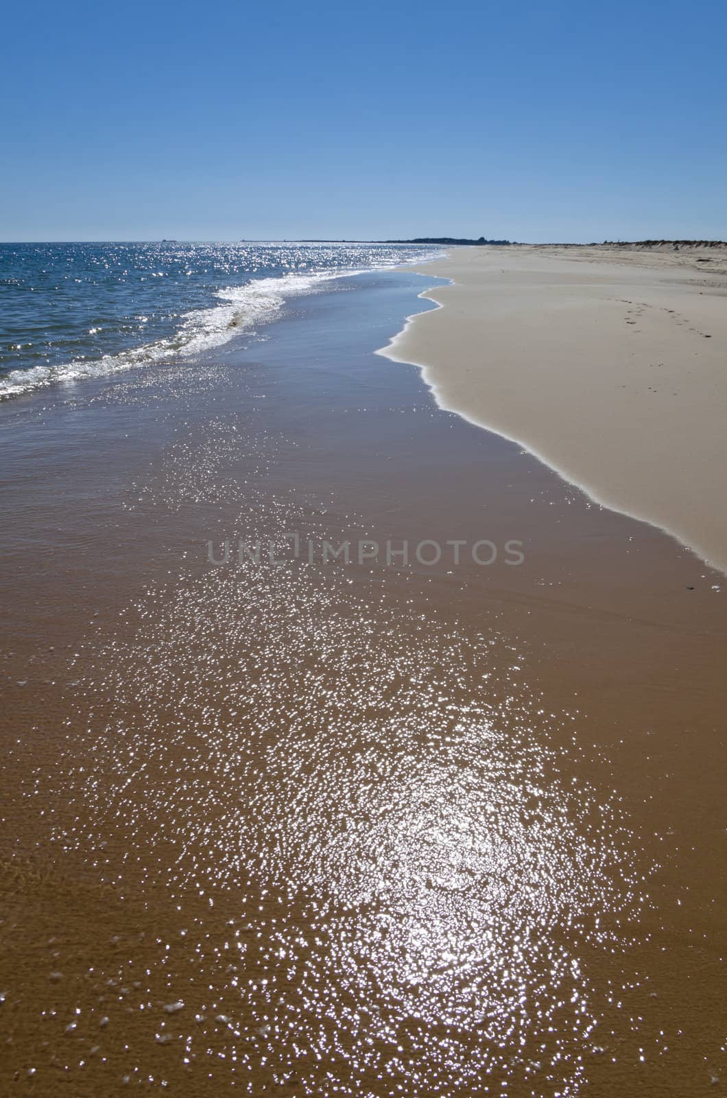 Reflection of the sun on the water over the sand