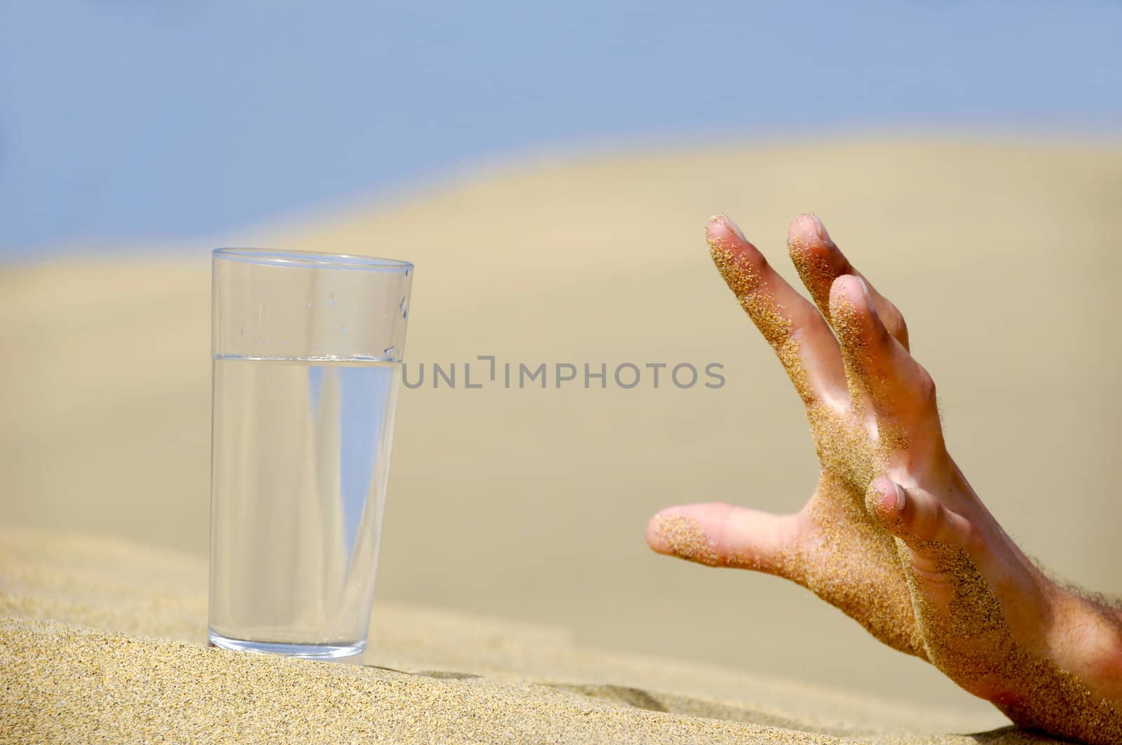 Hand is reaching for a fresh glass of cold water in desert.
