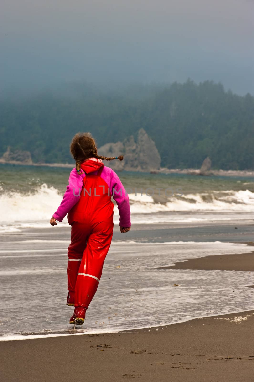 young girl in red rain clothes on ocean beach, Washngton, USA by rongreer