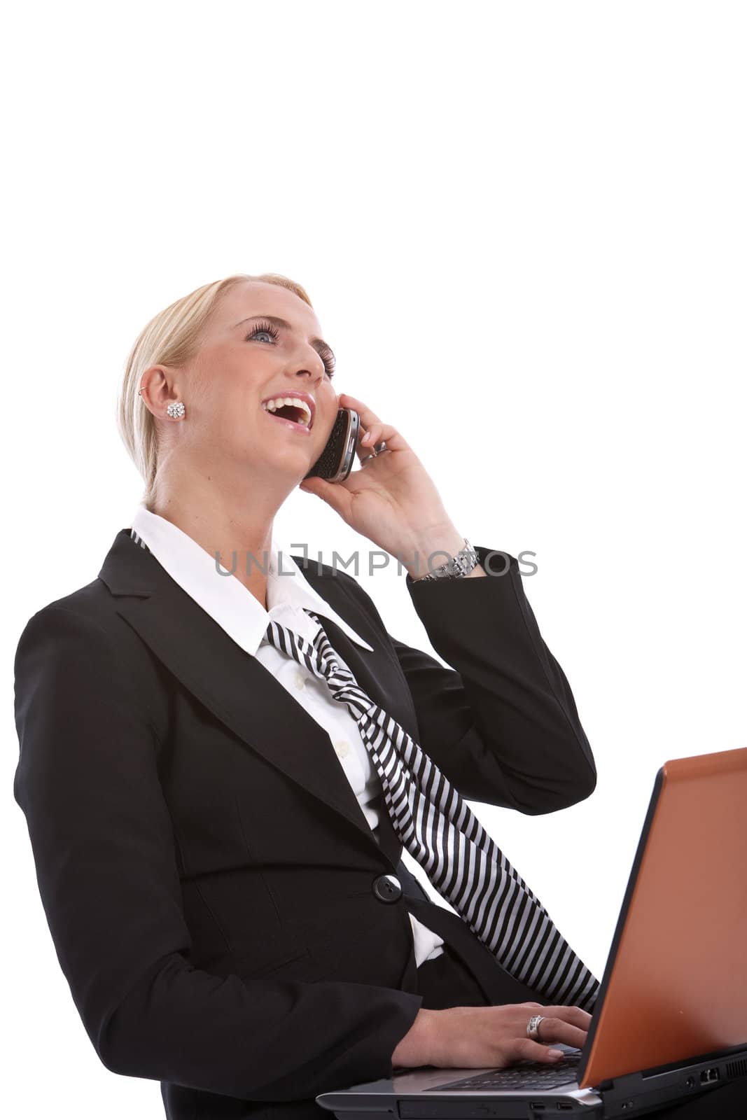 Businesswoman sitting and working on her laptop while laughing on the phone